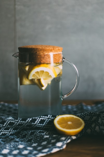 一个透明的玻璃罐，里面装满了切成片的柠檬，放在黑白相间的桌子上